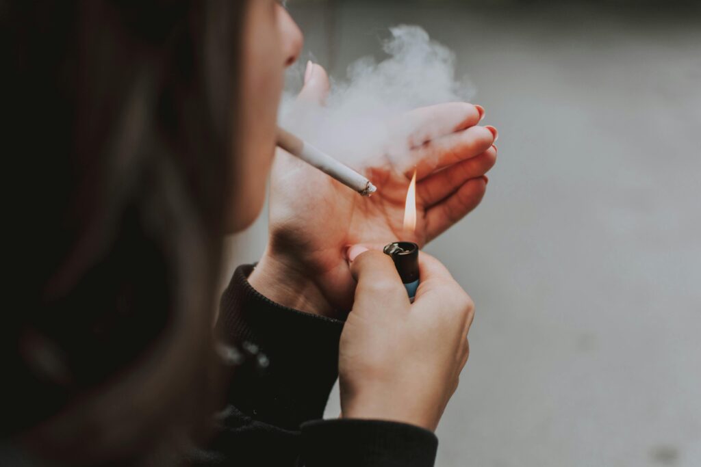 Person holding a cigarette pack with a store in the background, representing cigarette purchase nearby, Where Can I Buy Cigarettes Near Me?
